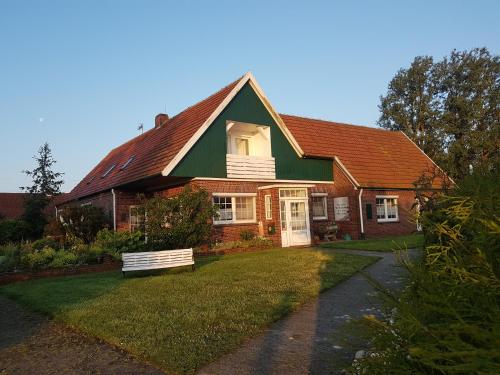 uma casa com um telhado verde e um jardim de relva em Birkenhof Neuharlingersiel em Neuharlingersiel