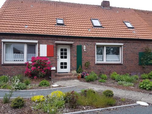 uma casa de tijolos com um telhado vermelho e algumas flores em Birkenhof Neuharlingersiel em Neuharlingersiel