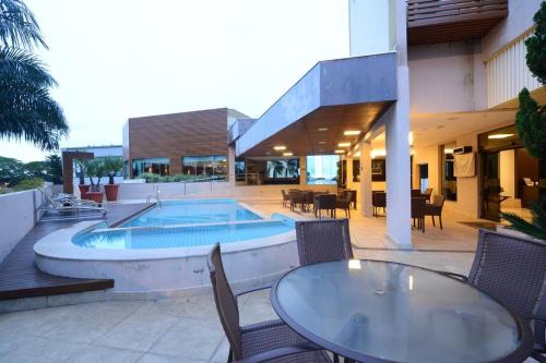 eine Terrasse mit einem Tisch und Stühlen sowie einem Pool in der Unterkunft Indaiá Park Hotel in Campo Grande