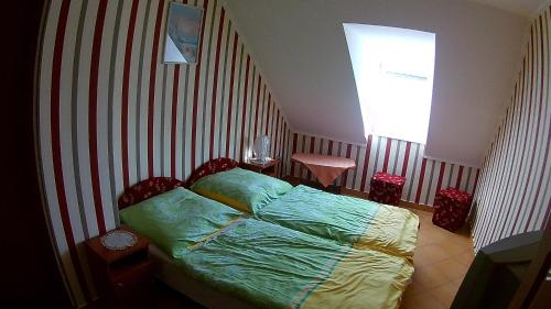 1 dormitorio con 1 cama con pared a rayas en Abigél Vendégház, en Harkány