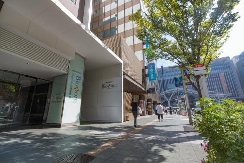 eine Person, die einen Bürgersteig neben einem Gebäude entlang läuft in der Unterkunft JR Kyushu Hotel Blossom Hakata Central in Fukuoka