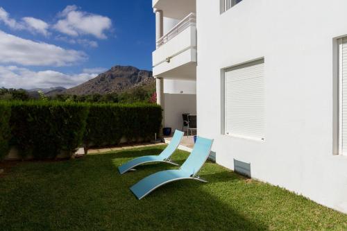 deux chaises bleues assises sur l'herbe à côté d'un bâtiment dans l'établissement Ground Floor with private garden Bellresguard, à Port de Pollença