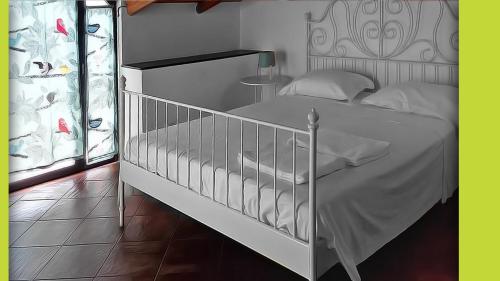 ein weißes Kinderbett in einem Zimmer mit einem Bett in der Unterkunft Le Coccole in Catania