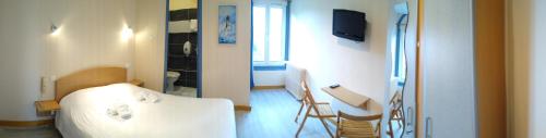 a room with a bed and a table and chairs at Hôtel des Sables Blancs in Douarnenez