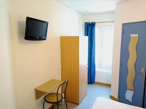 a room with a small table and a tv on the wall at Hôtel des Sables Blancs in Douarnenez