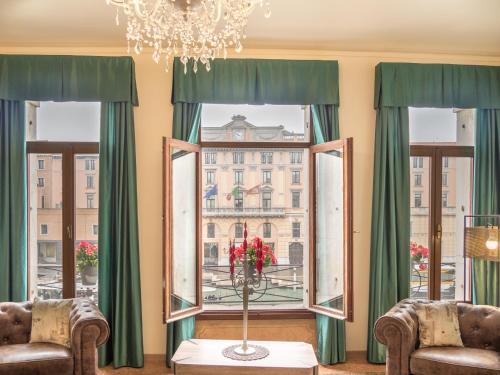 um quarto com duas cadeiras e uma janela com cortinas verdes em Grand Canal Suite by Wonderful Italy em Veneza