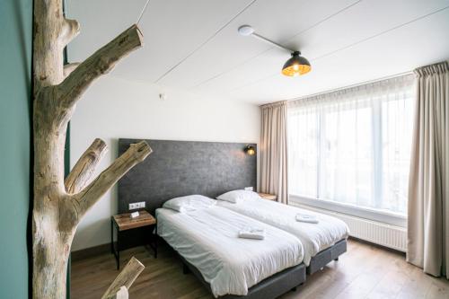 ein Schlafzimmer mit einem Bett und einem Baum darin in der Unterkunft Hotel & Eetk'fee de VLiK in Ospel