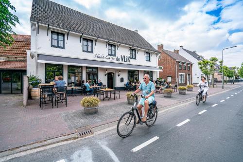 Ein paar Leute fahren Fahrrad die Straße runter. in der Unterkunft Hotel & Eetk'fee de VLiK in Ospel