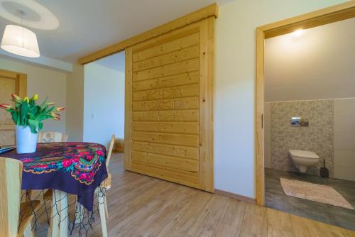 Camera con porta in legno, tavolo e servizi igienici. di Widokówka Tatry Pokoje i Apartamenty a Kościelisko