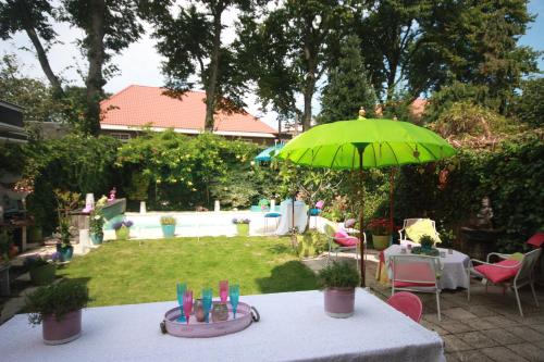 een tafel met een groene paraplu in een achtertuin bij De Pimpelmees in Den Haag