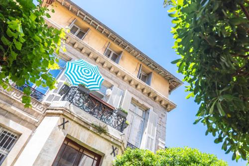 um edifício com um guarda-chuva azul e branco numa varanda em La Maïoun Guesthouse em Nice