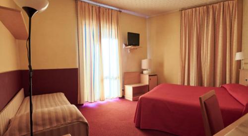 a hotel room with a red bed and a window at Hotel Atlantic in Arona