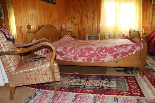 een slaapkamer met een bed, een stoel en een tapijt bij Sadyba Lukacha in Zhdenievo