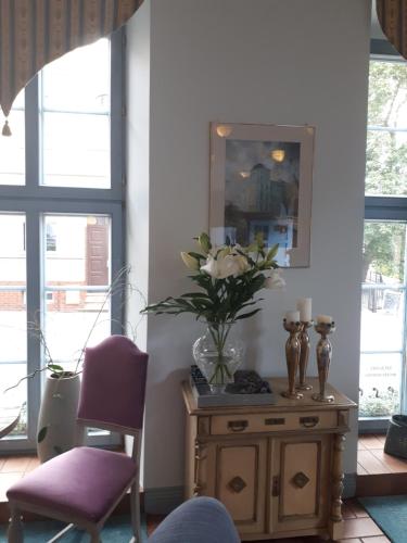 a room with a table with a vase of flowers on it at Hotel Marmułowski in Wejherowo