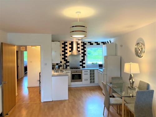 una cucina con elettrodomestici bianchi e tavolo in vetro di Firpark City Apartment - 2 Bedrooms a Glasgow