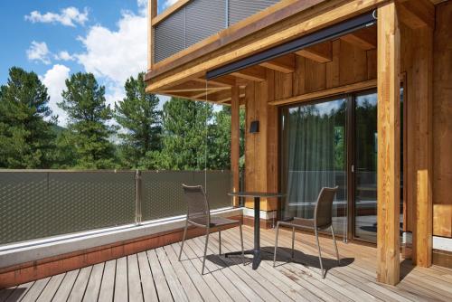 una terraza de madera con mesa y sillas. en Alpine Lodge Chesa a la Punt, en Pontresina