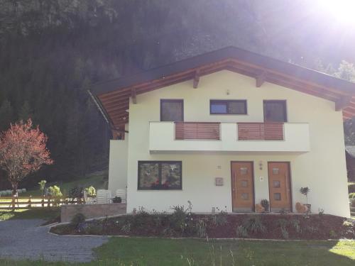 Casa blanca con puertas marrones y patio en Apart Alpenflair, en Sankt Leonhard im Pitztal