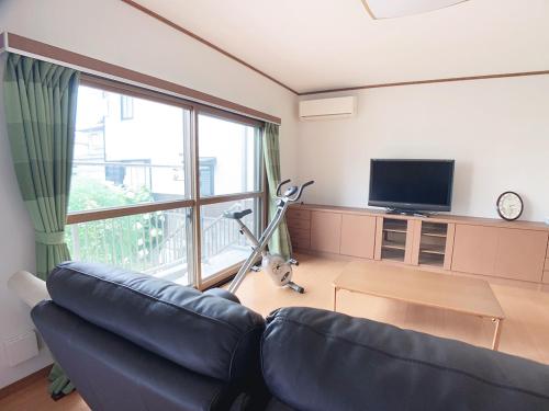 ein Wohnzimmer mit einem Sofa und einem großen Fenster in der Unterkunft Itsukaichi First Villa Hiroshima in Hiroshima