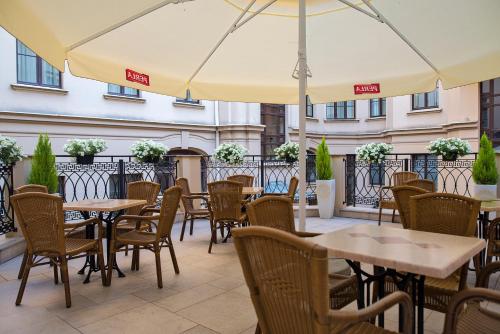 un patio esterno con tavoli, sedie e ombrelloni di IBB Hotel Grand Hotel Lublin a Lublino