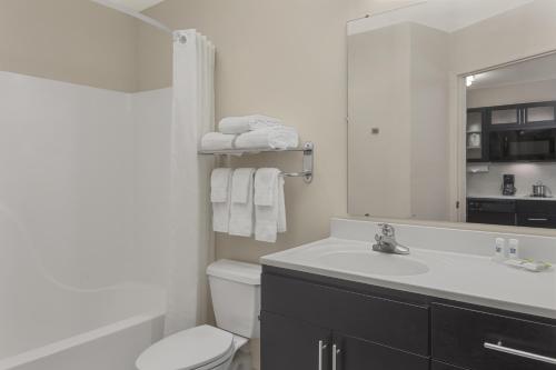 bagno con lavandino, servizi igienici e specchio di Candlewood Suites Raleigh Crabtree by IHG a Raleigh