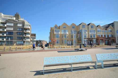 due panche sedute di fronte a un grande edificio di Beach House Rodine - free parking & bikes a Scheveningen