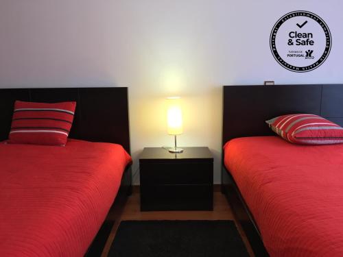 um quarto com 2 camas com lençóis vermelhos e um candeeiro em São Martinho do Porto Beach Apartment em São Martinho do Porto