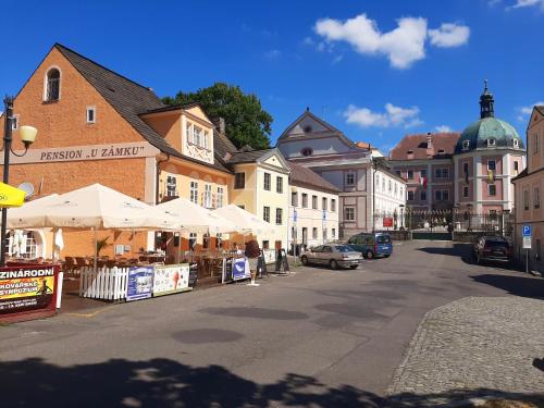 una via cittadina con edifici, tavoli e ombrelloni di Penzion - Restaurant U Zámku a Bečov nad Teplou