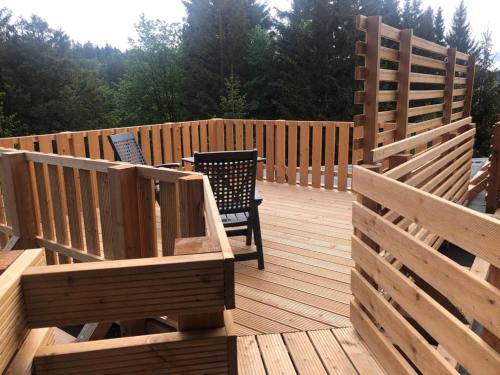 una terraza de madera con 2 sillas y una valla en Hotel Carlsruh, en Braunlage