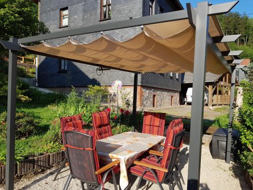 een tafel en stoelen onder een paraplu in een tuin bij Ferienwohnung Baacke in Ruhla