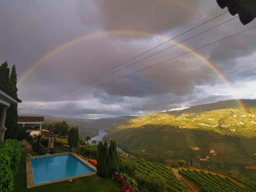 a rainbow over a villa with a swimming pool at Casa De Canilhas in Mesão Frio