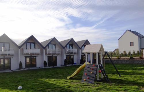 einen Spielplatz mit Rutsche vor einem Haus in der Unterkunft White Houses Rewal in Rewal