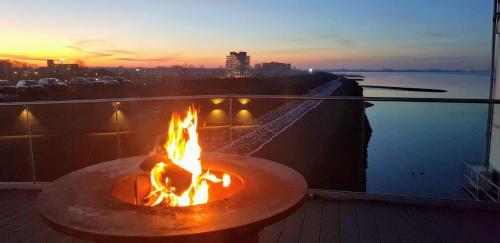 una hoguera en un balcón con la puesta de sol en el fondo en Eemshotel, en Delfzijl