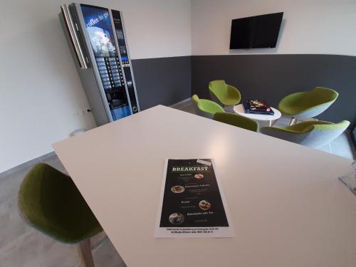 a book sitting on top of a white table with green chairs at Office Base Bad Vöslau MOTEL in Bad Vöslau