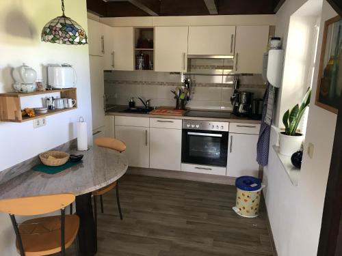 eine Küche mit weißen Schränken und einem Tisch mit Stühlen in der Unterkunft Kleine Ferienwohnung bei Kappeln an der Schlei in Kappeln