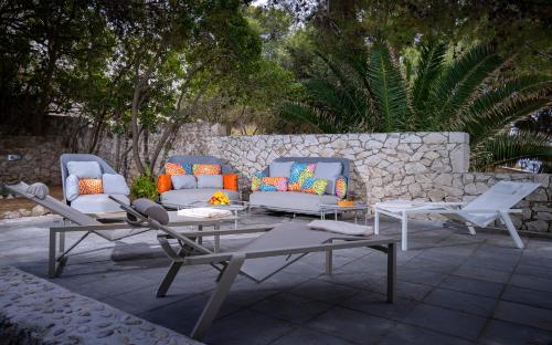 a patio with two couches and a table and chairs at Pine Beach Villa in Hvar