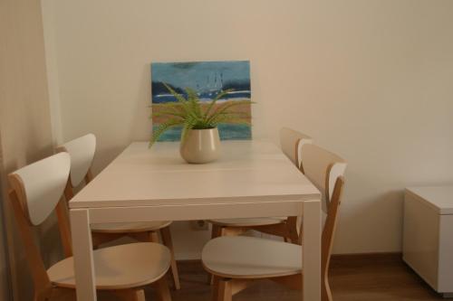 a white dining room table with chairs and a vase on it at Apartamentos Apartour Bormujos in Bormujos