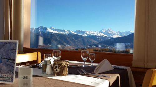 een tafel met wijnglazen en uitzicht op de bergen bij Hôtel Splendide in Crans-Montana