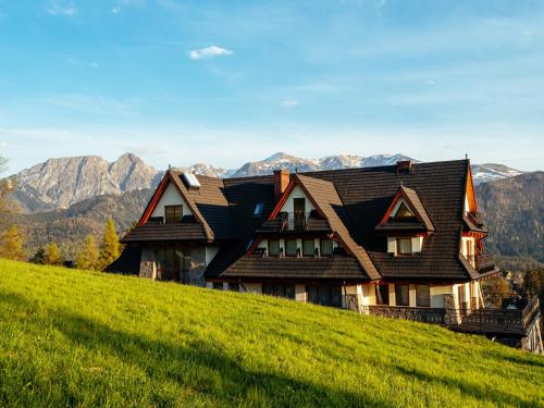 a house on a hill with mountains in the background at Strama Kościelisko in Kościelisko