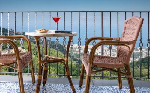 een tafel en stoelen met een glas wijn op een balkon bij Grand Hotel Due Golfi in SantʼAgata sui Due Golfi