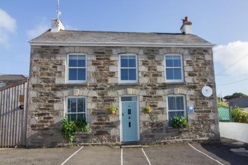 une ancienne maison en pierre avec une porte bleue dans l'établissement Utopia Apartments, à Perranporth