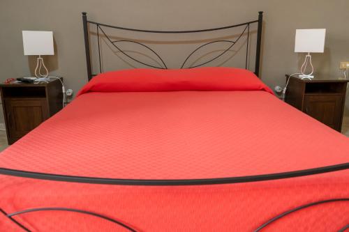 een slaapkamer met een rood bed en 2 nachtkastjes bij B&B Santi Medici in Bitonto