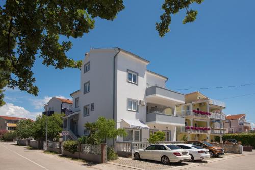 ein weißes Gebäude mit davor geparkt in der Unterkunft Apartments Lovrić in Vodice