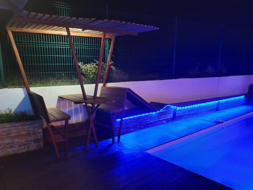 una piscina con una mesa y una silla por la noche en Villa Mango, en Le Gosier