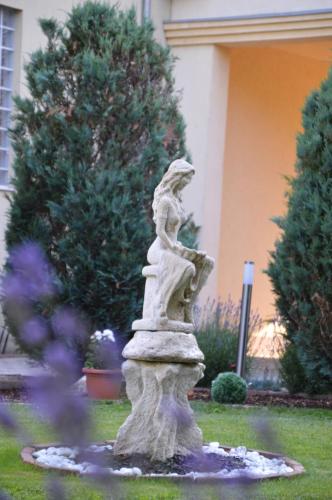 Eine Statue einer Frau, die auf einem Brunnen im Hof sitzt. in der Unterkunft Hotel Harka in Harkány