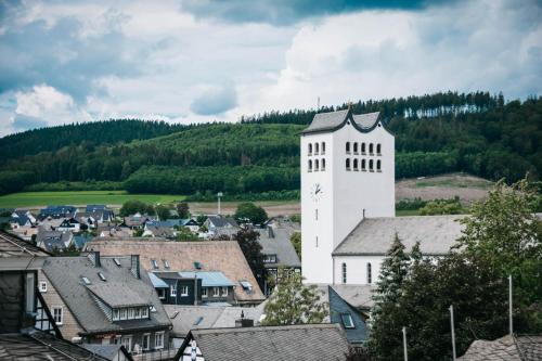 un edificio bianco con una torre dell'orologio in una città di Parkhotel Schmallenberg a Schmallenberg