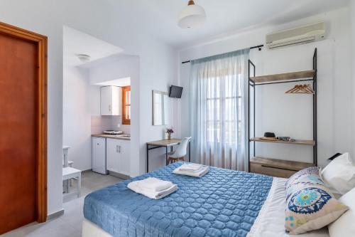 een slaapkamer met een blauw bed en een keuken bij Nepheles in Skopelos Town