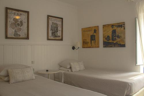 two beds in a room with posters on the wall at Vinnus Guesthouse in Ericeira