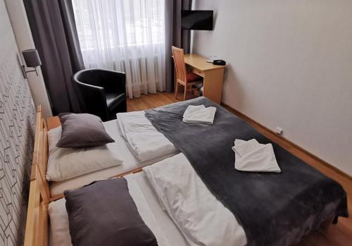 2 bedden in een kamer met een bureau bij Hotel Preveza in Spišská Nová Ves