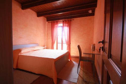 a bedroom with a bed and a window with a chair at B&B Linu Ruiu in Santu Lussurgiu