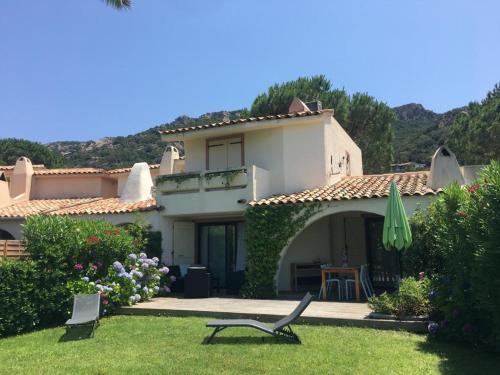 a house with an umbrella and chairs in the yard at Villa 8 au Village Marin in Porto-Vecchio